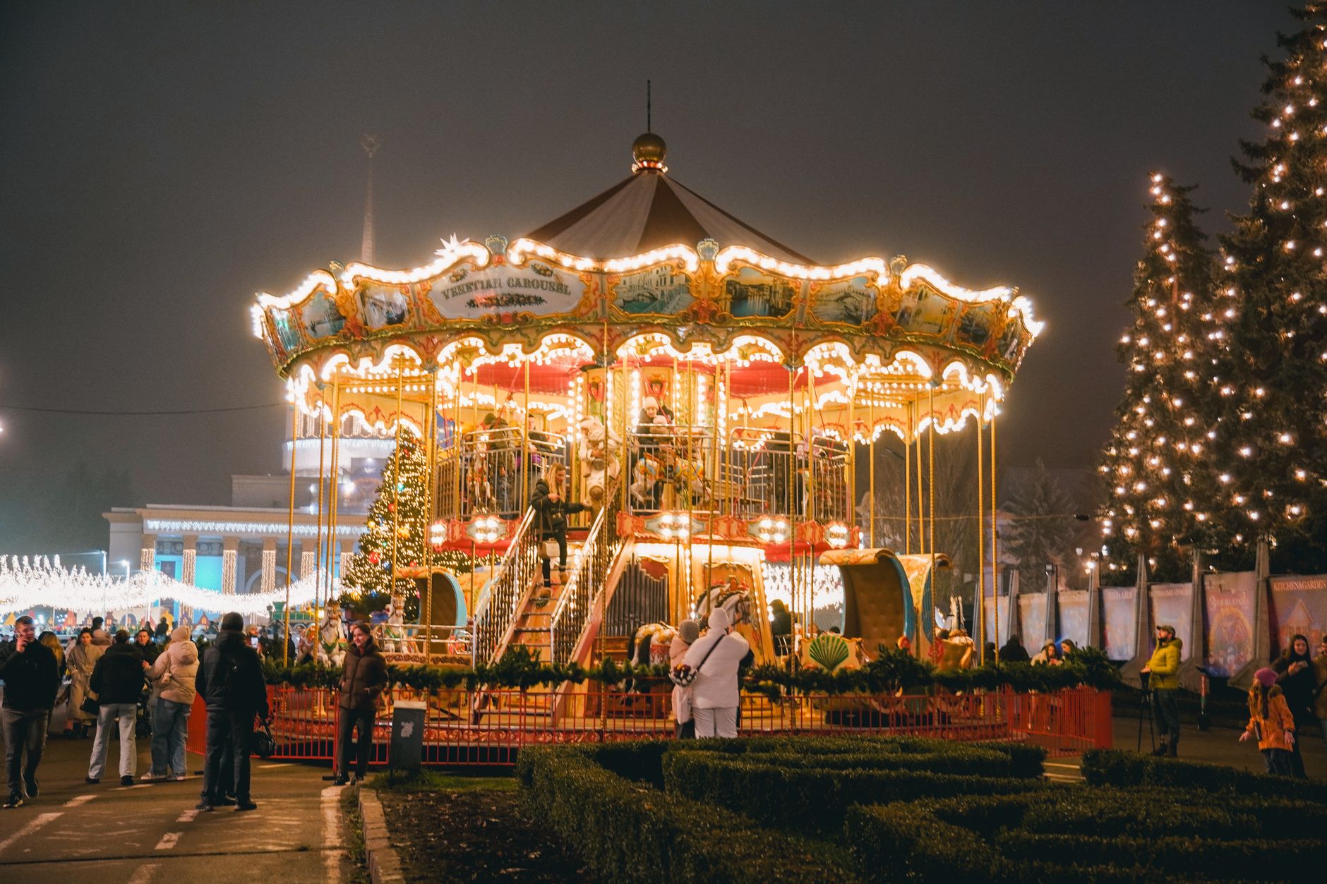 A vibrant Christmas carousel in Kyiv, Ukraine at night, surrounded by people enjoying the holiday spirit. — Trójmiasto