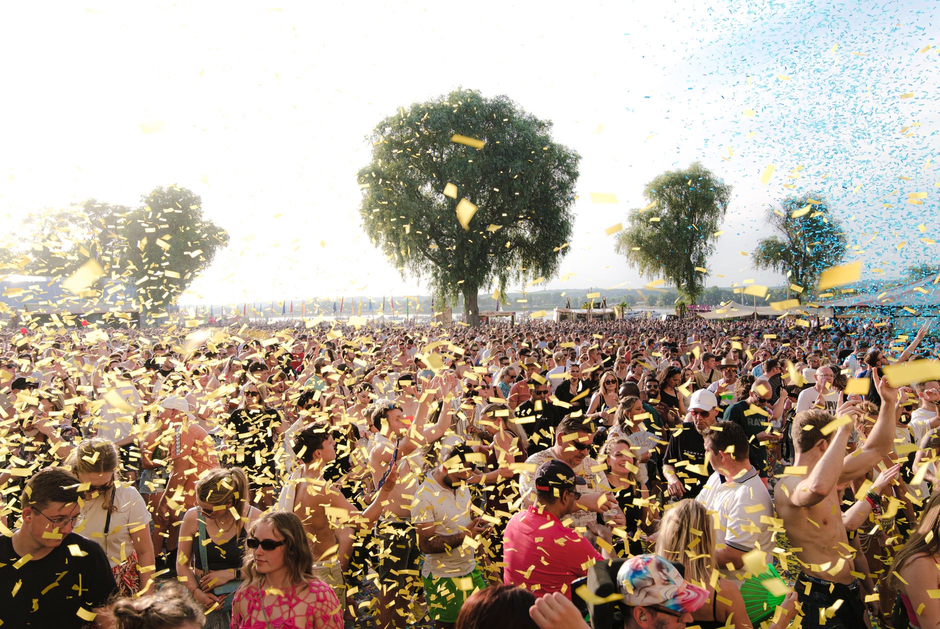 A lively crowd enjoying an outdoor music festival with confetti under a sunny sky. — Trójmiasto