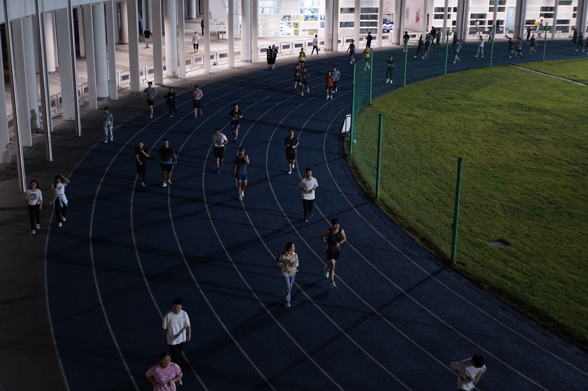 A group of people jogging on an outdoor track in the evening, showcasing urban fitness culture. — Trójmiasto