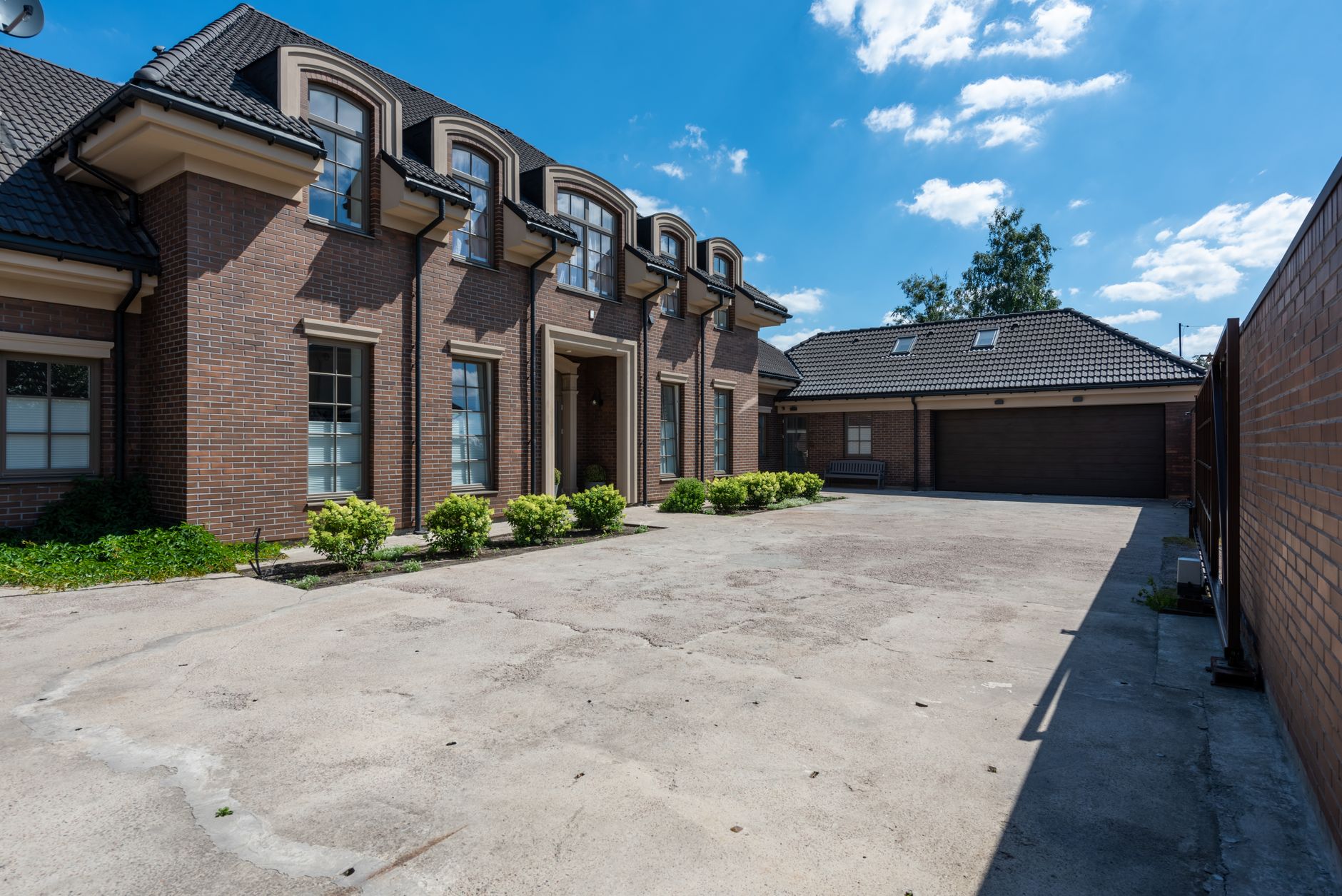 Elegant brick house exterior with a large driveway under a clear blue sky. — Trójmiasto