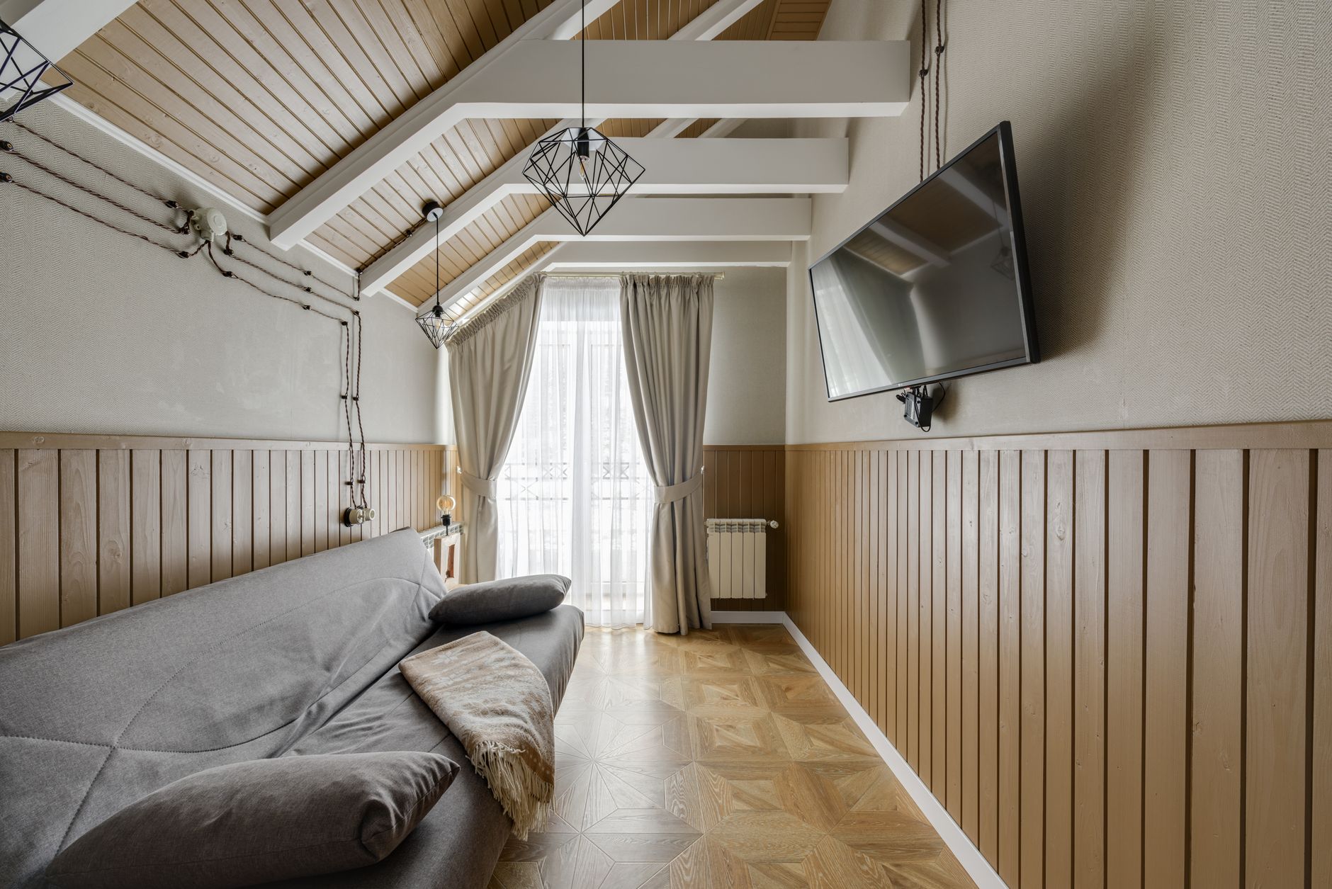 Stylish living room with a couch, TV, and natural light from large window. — Trójmiasto