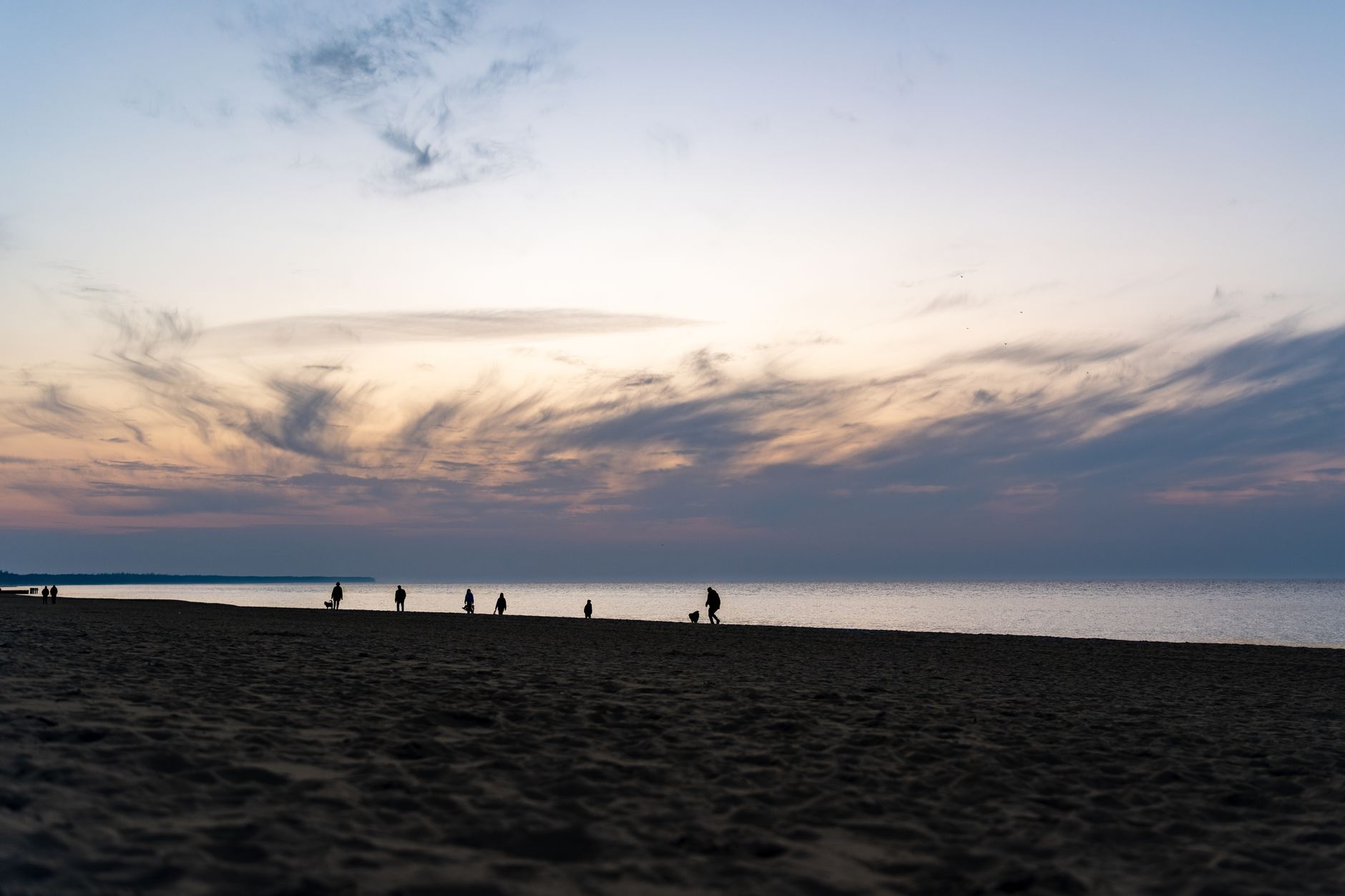 Silhouettes of people walking on Kołobrzeg beach during a stunning sunset. — Trójmiasto