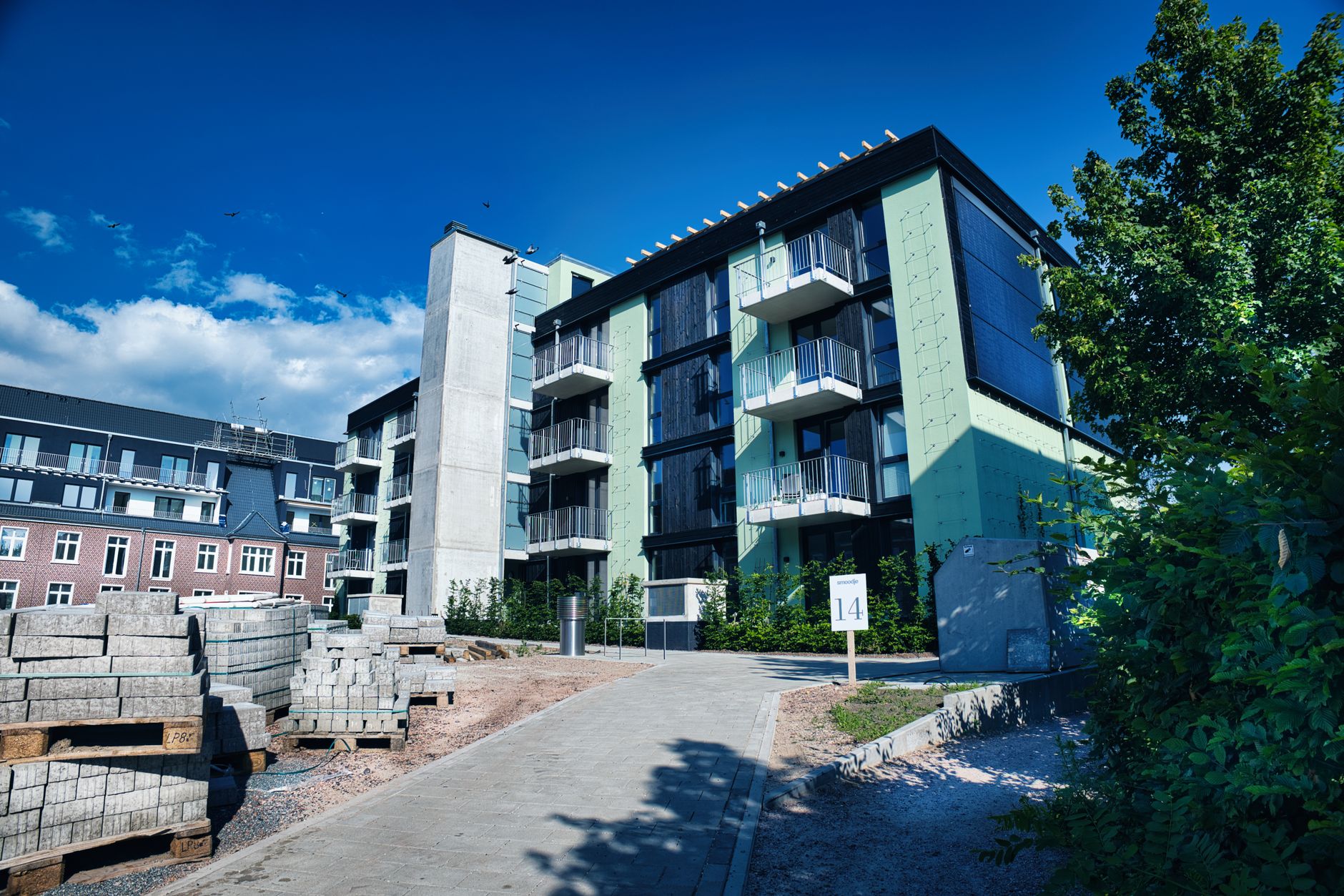A contemporary apartment building with green accents and balconies in an urban setting. — Trójmiasto