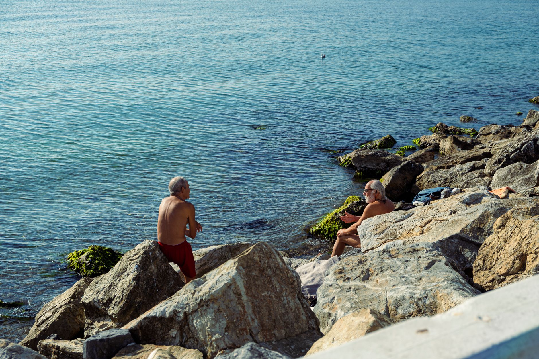 Two senior men enjoying a quiet moment on the rocks by the sea in Istanbul, Türkiye. — Trójmiasto