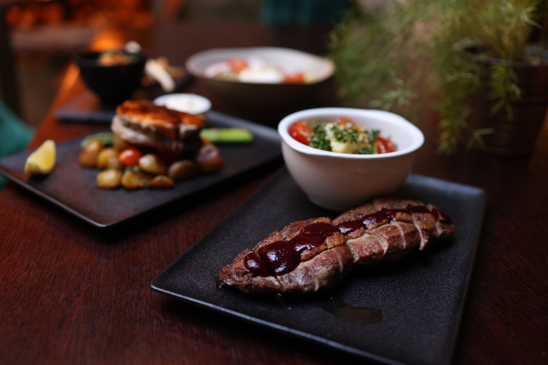 Gourmet steak with sauce and sides on a dark plate, showcasing fine dining ambiance. — Trójmiasto