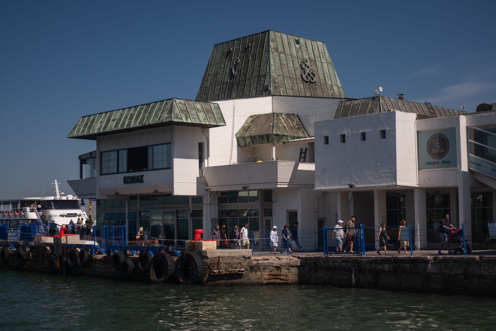 Tourists and locals at the busy Izmir ferry terminal on a sunny day. — Trójmiasto