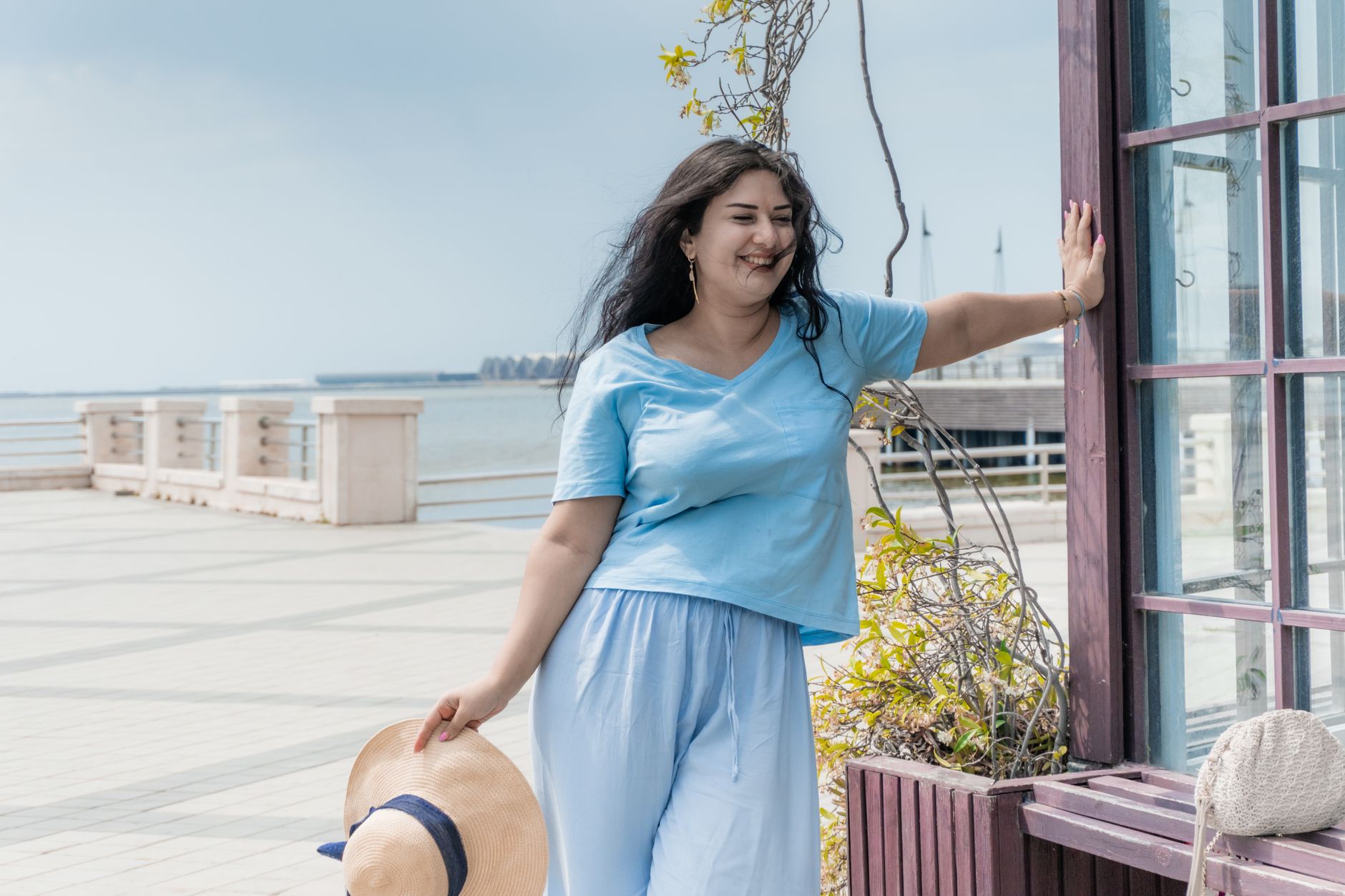 A smiling woman enjoys a sunny day at the Baku waterfront, wearing casual summer fashion. — Trójmiasto