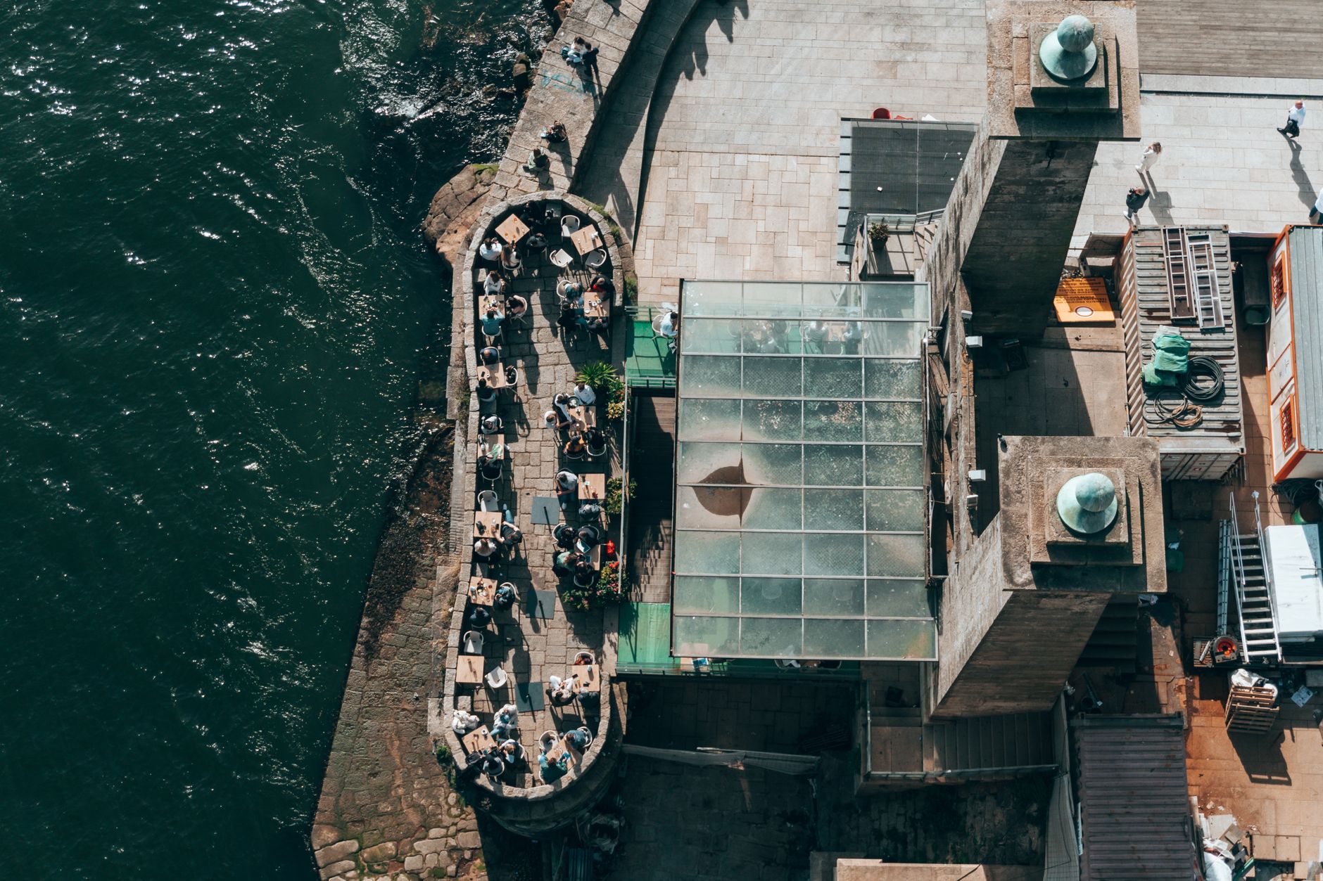 Top-down view of a riverside restaurant in Porto, Portugal, with people dining outdoors. — Trójmiasto