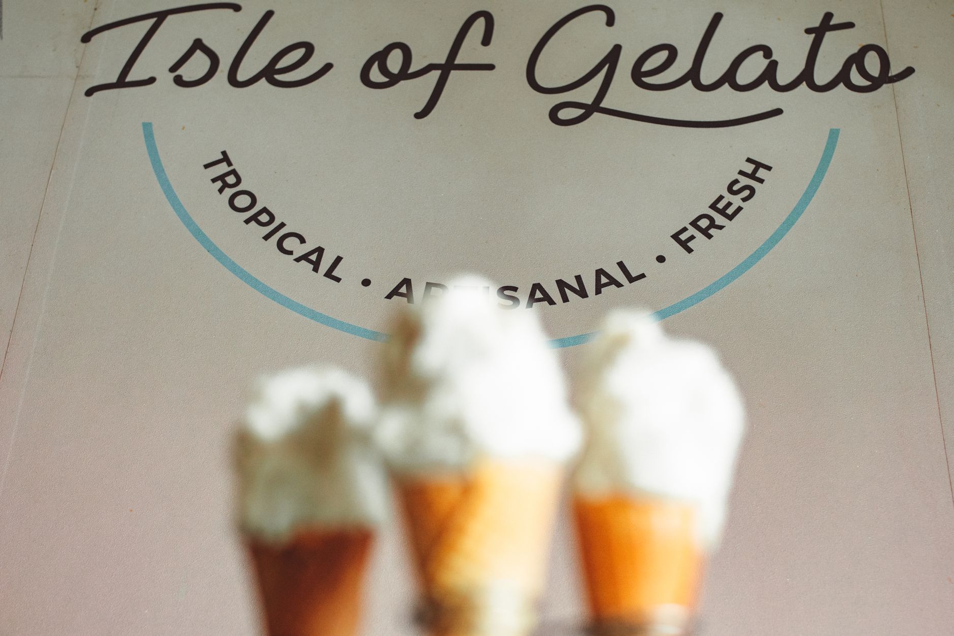 Close-up of gelato cones with tropical-themed signage in the background, showcasing fresh flavors. — Trójmiasto
