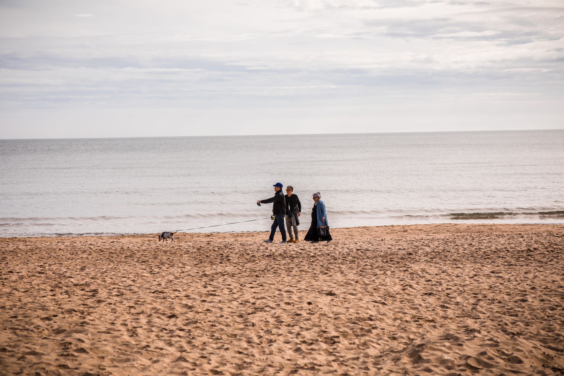 Family enjoying a walk with dog on Bournemouth beach, England. Serene seaside setting. — Trójmiasto