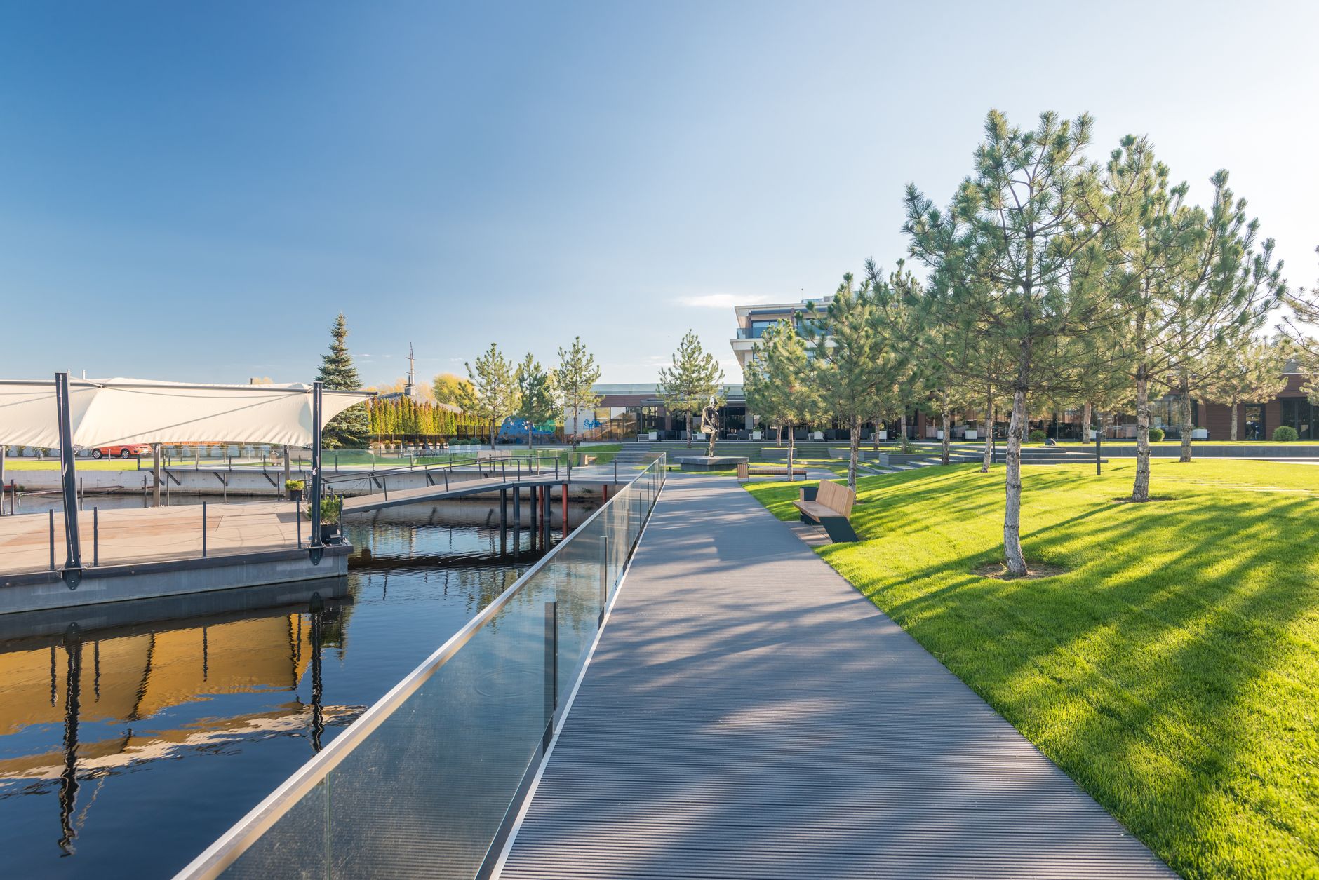 Peaceful lakeside park with modern promenade and trees under a clear sky. — Trójmiasto