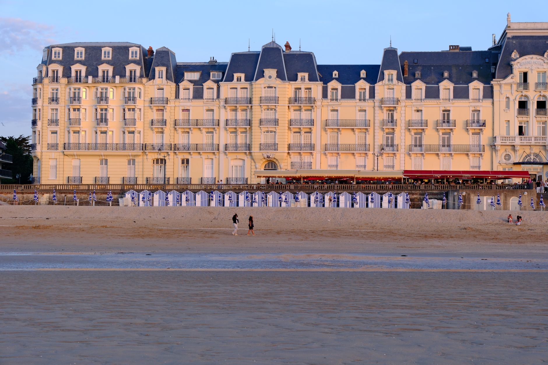 Charming view of Cabourg's Grand Hotel with beach in front, captured at sunset. — Trójmiasto