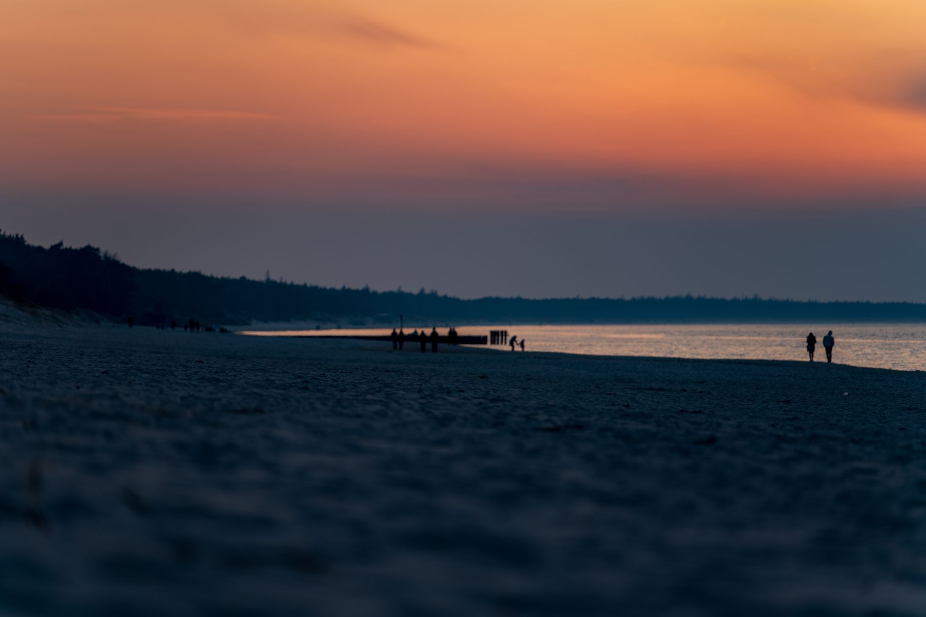 Tranquil sunset view at Kołobrzeg beach with silhouettes of visitors enjoying the serene evening. — Trójmiasto
