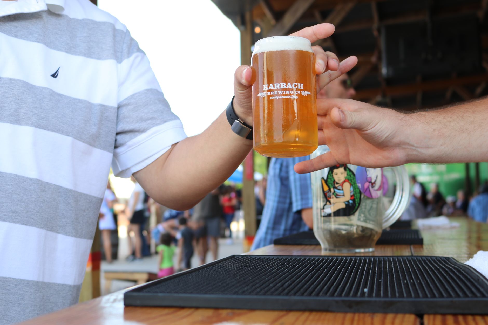 Two people exchange a freshly poured beer outdoors by the bar counter. — Trójmiasto