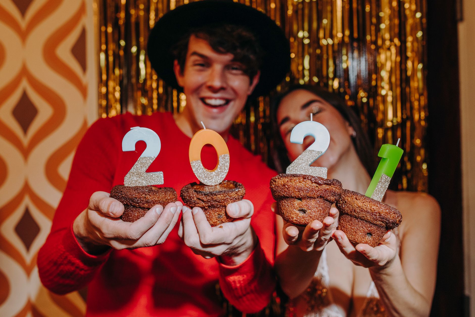 Happy couple celebrating New Year's Eve with cupcakes and 2021 candles. — Trójmiasto