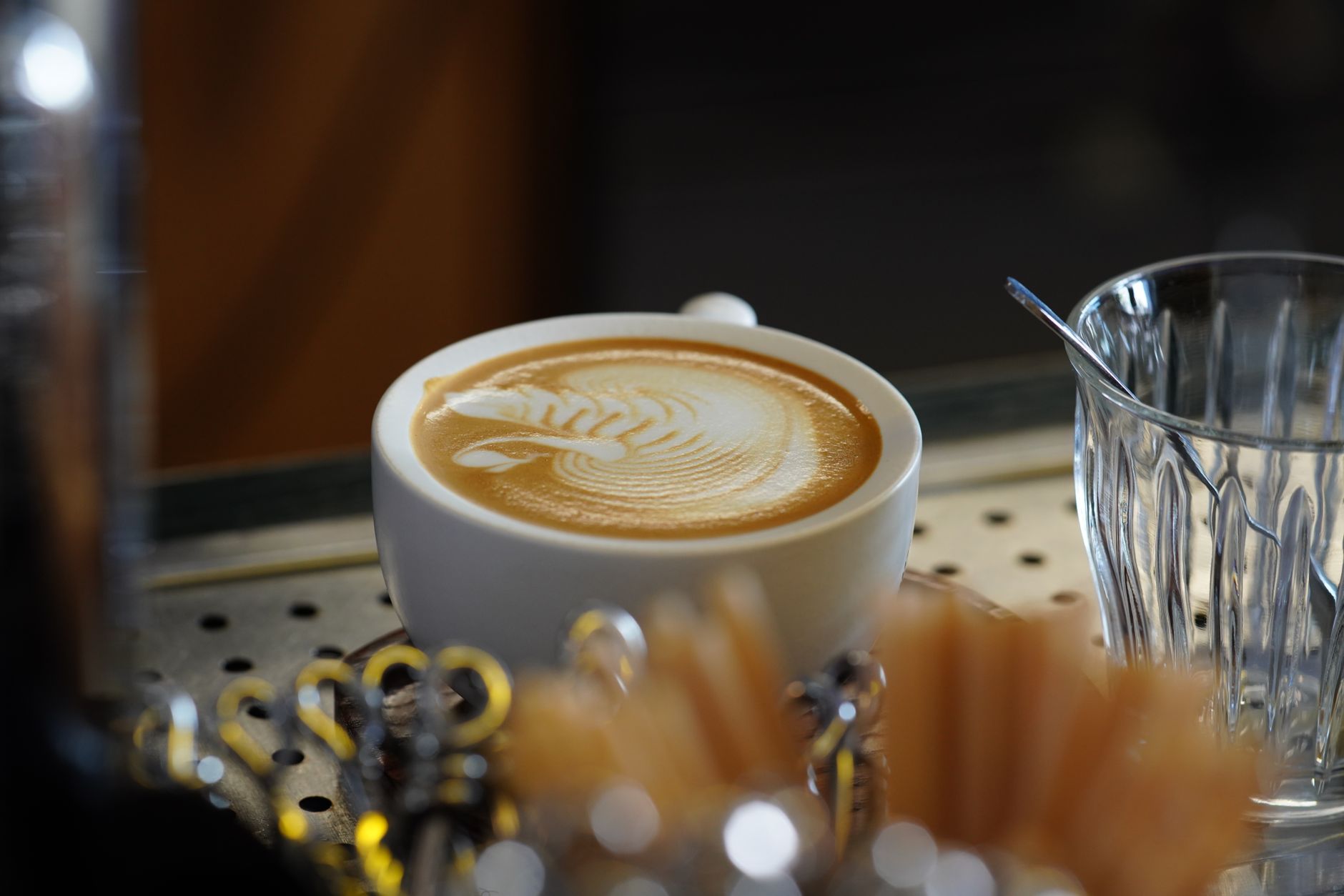 A close-up of a beautifully crafted latte with intricate latte art, served in a stylish café setting. — Trójmiasto