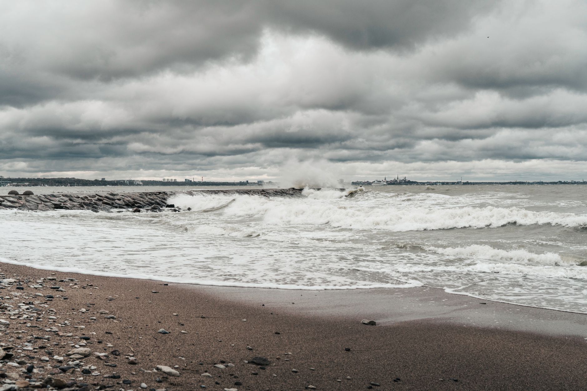 A moody, dramatic view of stormy waves crashing on an Estonian beach under overcast skies. — Trójmiasto