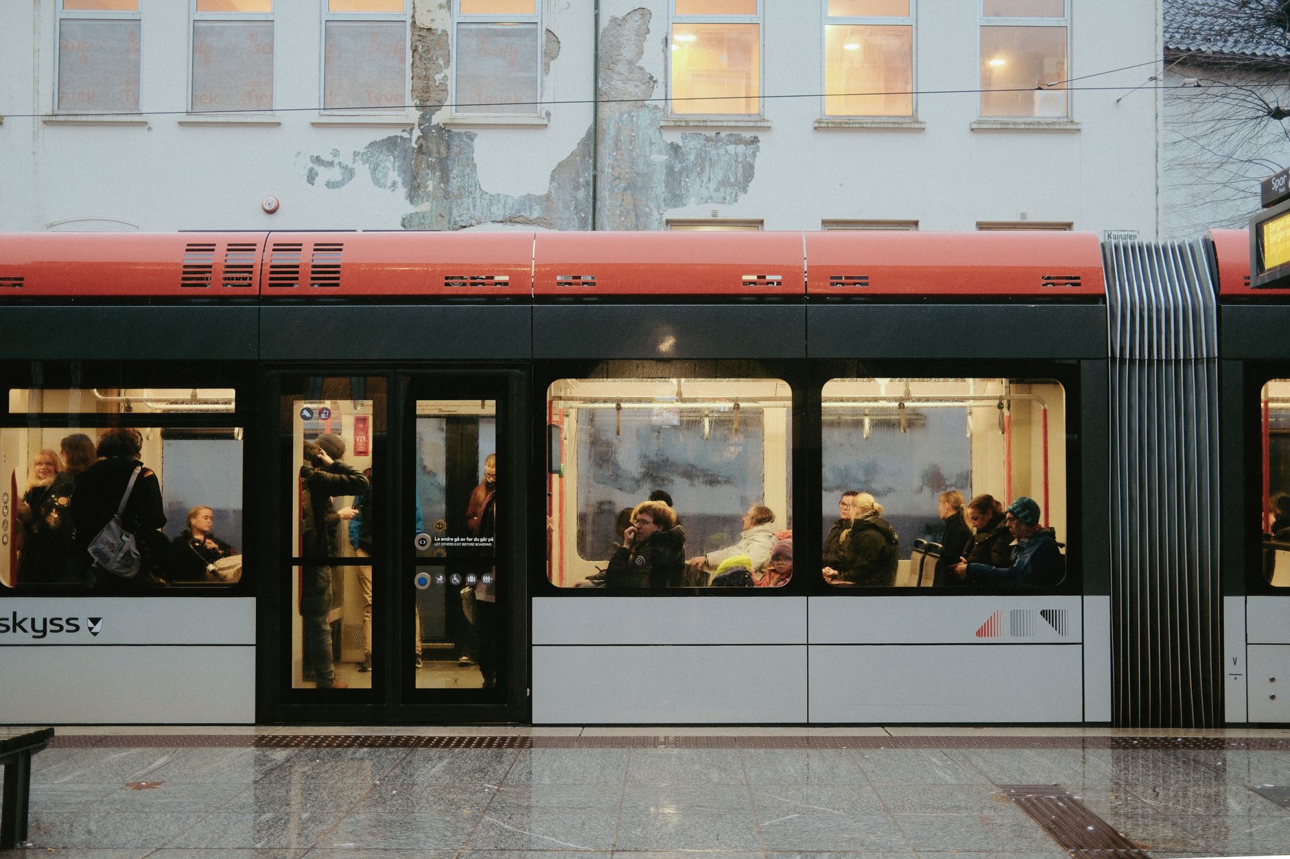 Commuters inside a red and white city tram in a European urban environment. — Trójmiasto