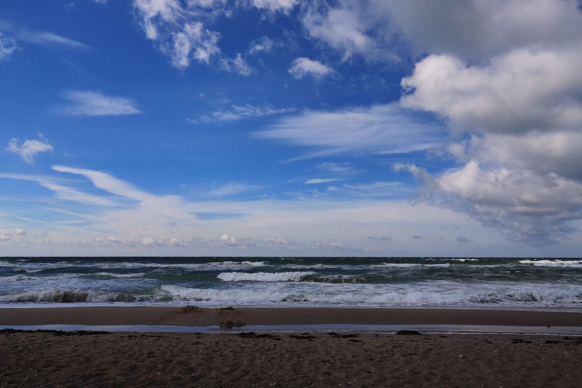 Beautiful view of the Baltic Sea in Denmark with a sandy beach, waves, and dramatic clouds in a clear sky. — Trójmiasto