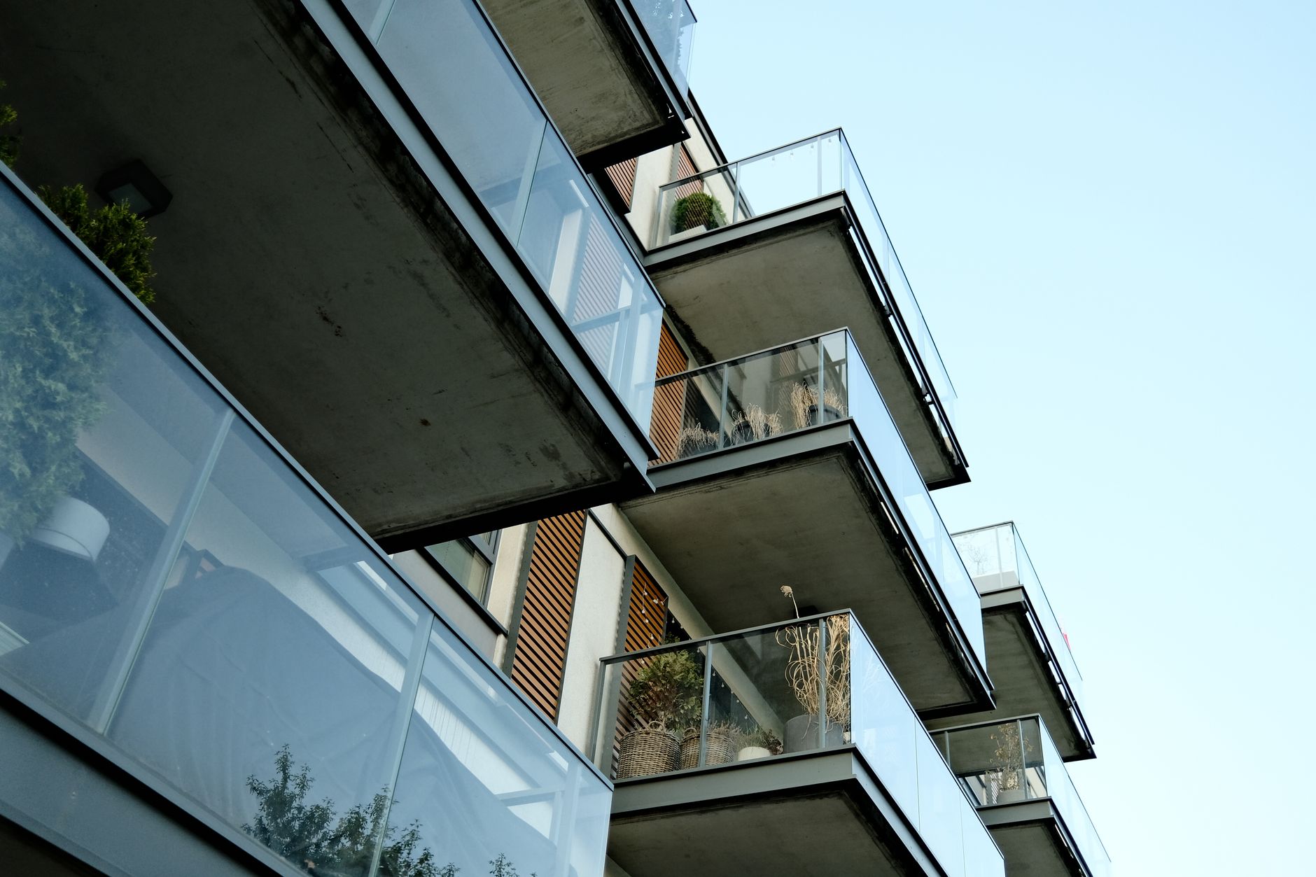 A modern residential building's glass balconies under a clear sky, showcasing contemporary architecture. — Trójmiasto