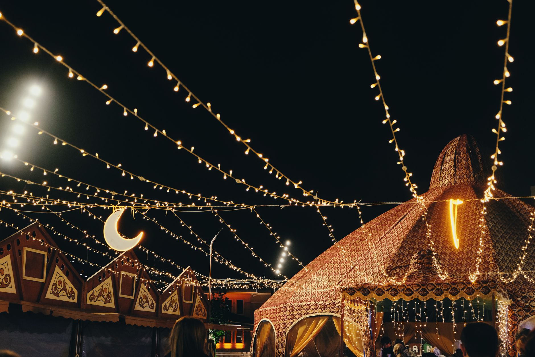A lively night festival scene with decorative tents and string lights creating a festive atmosphere. — Trójmiasto