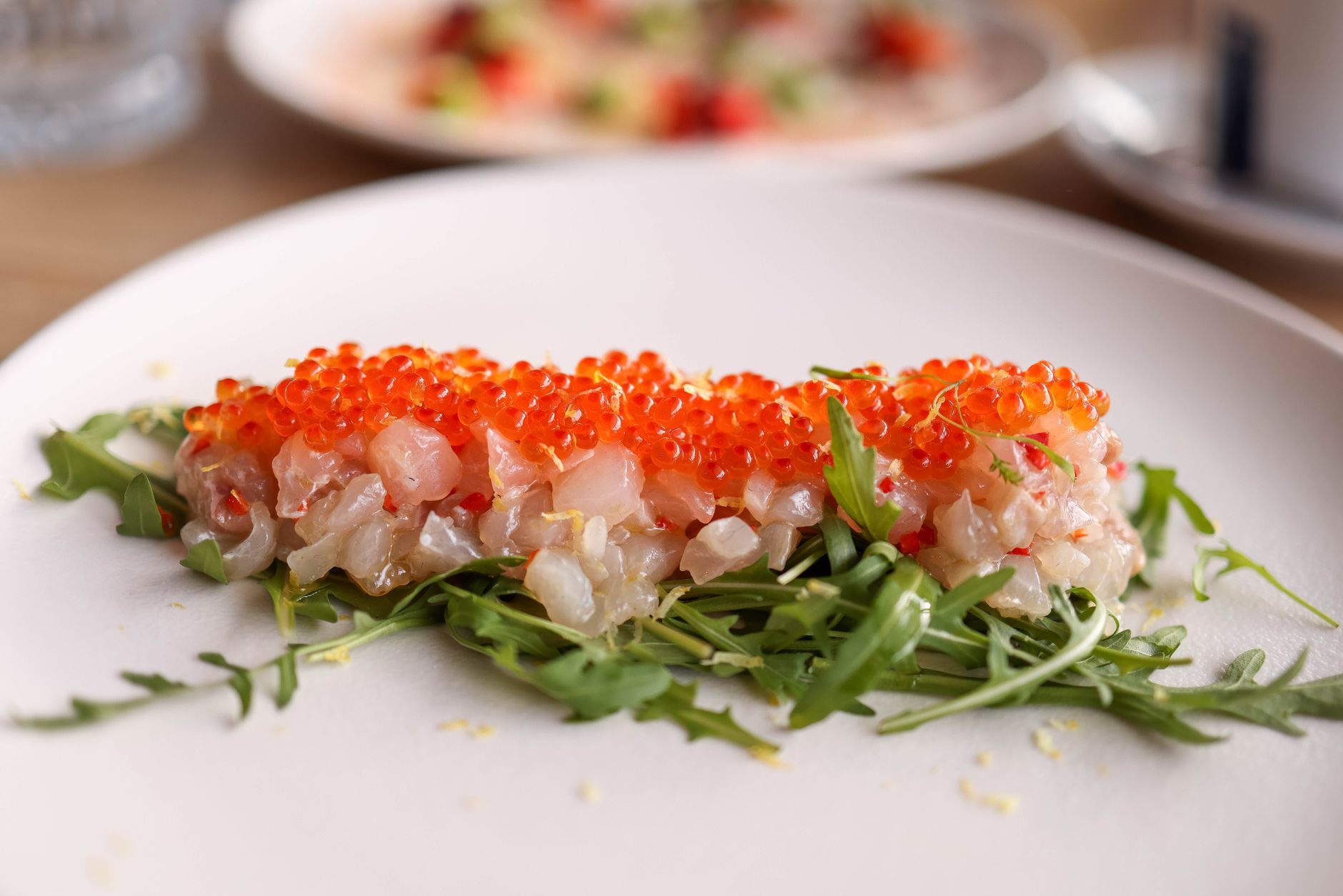 Fresh fish tartare topped with salmon roe on a bed of arugula, beautifully plated for fine dining. — Trójmiasto