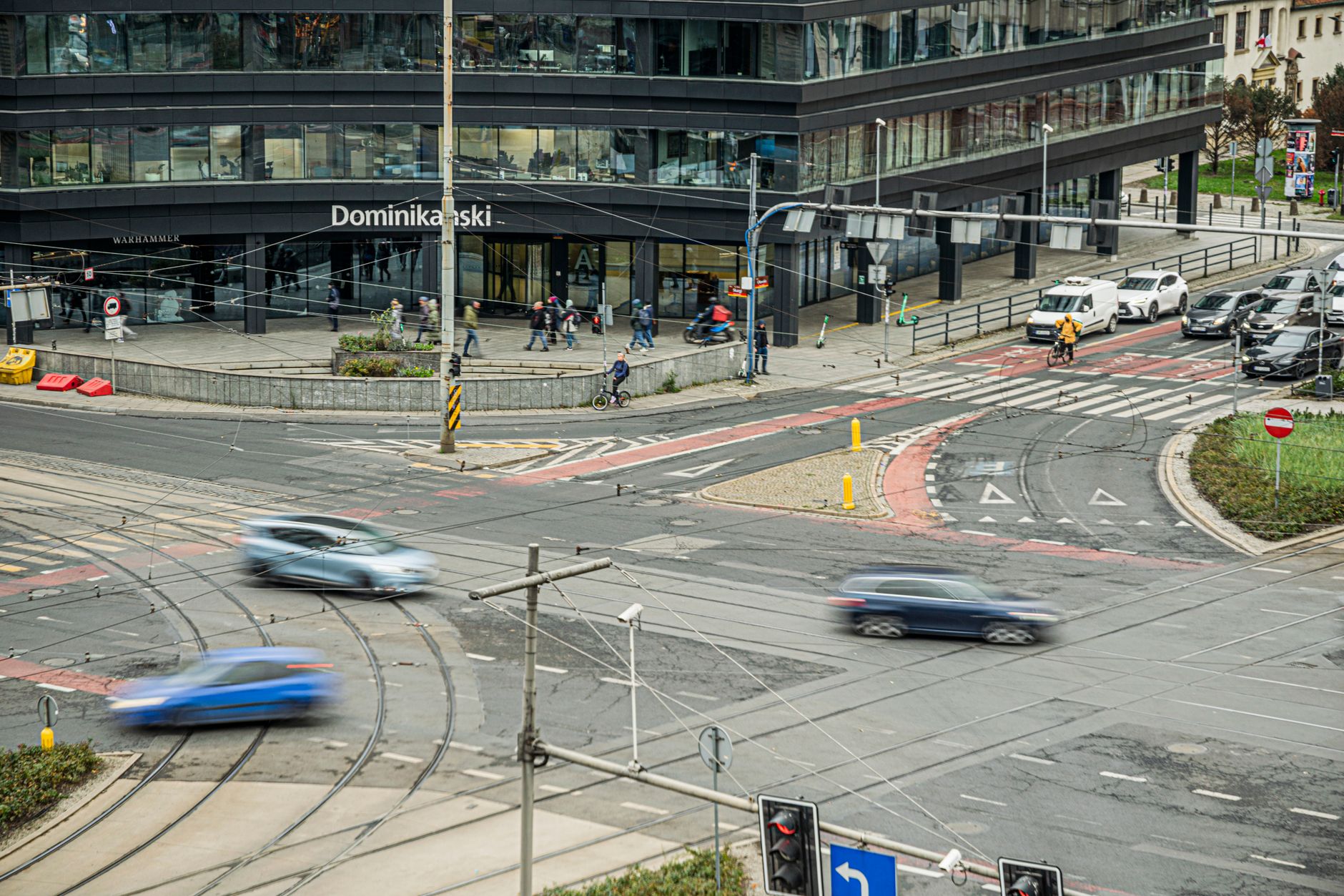 A bustling city intersection near a modern office building with blurred traffic and pedestrians. — Trójmiasto