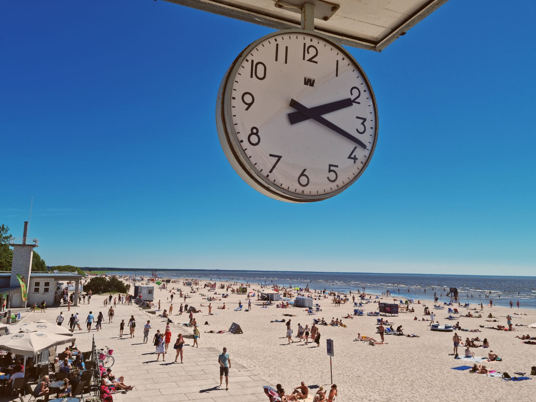 A lively summer day at Pärnu Beach captured under a clear blue sky with a prominent clock view. — Trójmiasto