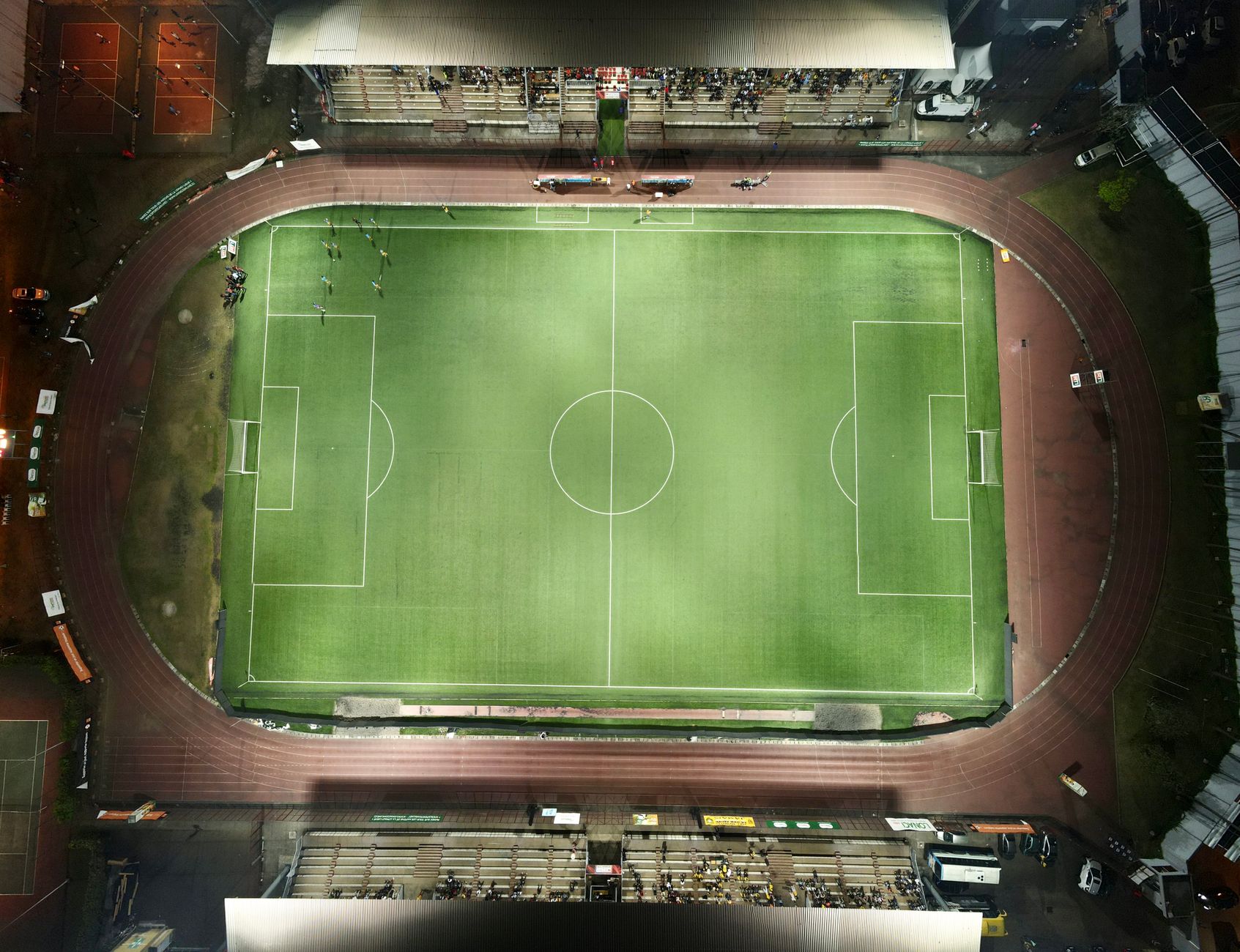 Top-down aerial view of a football stadium illuminated at night with minimal crowd. — Trójmiasto