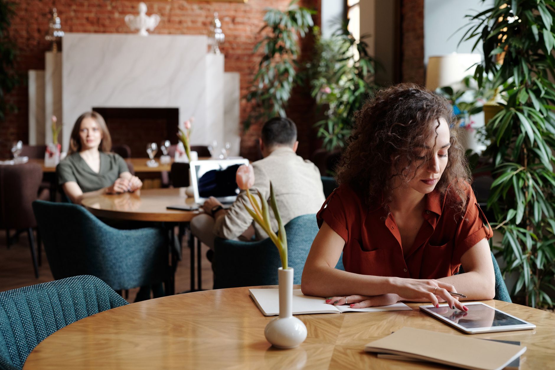 Woman engaged in remote work on tablet in a stylish cafe setting. — Trójmiasto